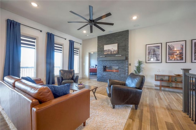 living room with recessed lighting, a fireplace, light wood-style floors, and ceiling fan