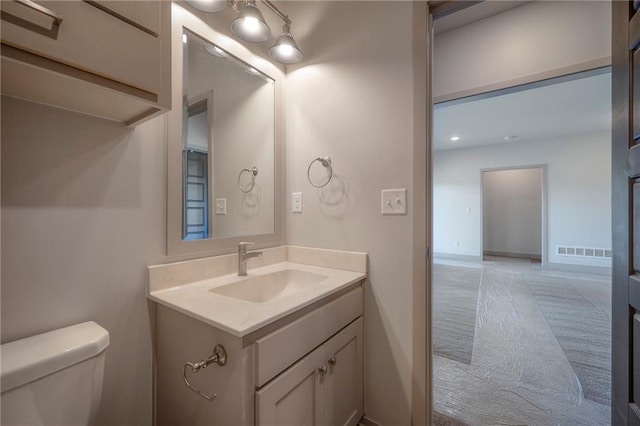 half bathroom with visible vents, toilet, and vanity