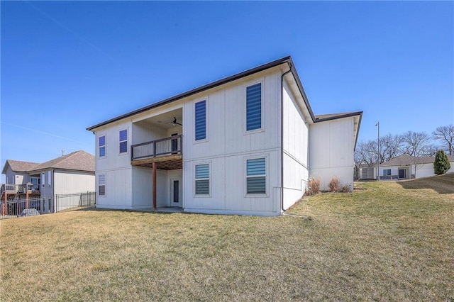 back of house with a balcony, ceiling fan, a yard, and fence