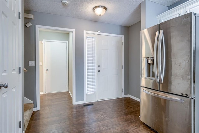 kitchen featuring baseboards, stainless steel fridge, a textured ceiling, and dark wood-style flooring