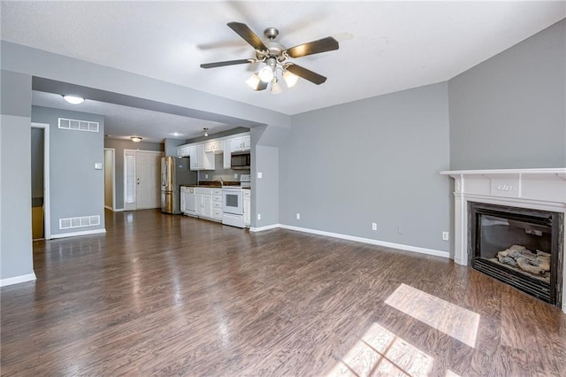 unfurnished living room with visible vents, baseboards, and dark wood-style floors