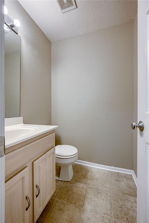 bathroom with vanity, baseboards, visible vents, a textured ceiling, and toilet