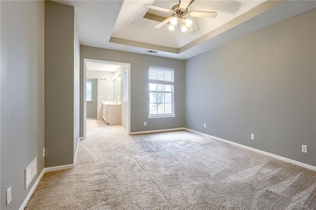 unfurnished room featuring visible vents, a raised ceiling, and baseboards