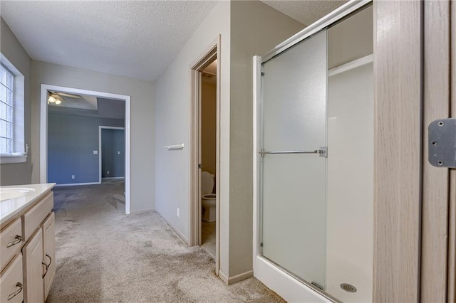 bathroom featuring vanity, toilet, a stall shower, and a textured ceiling