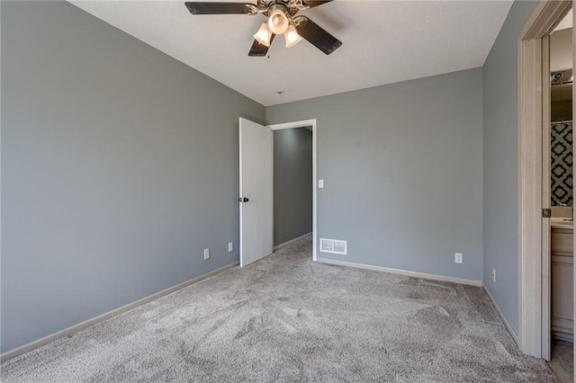 carpeted spare room featuring visible vents, ceiling fan, and baseboards