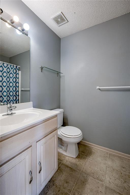 full bathroom with vanity, baseboards, visible vents, a textured ceiling, and toilet