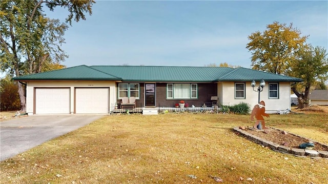 single story home with a garage, a front lawn, metal roof, and driveway