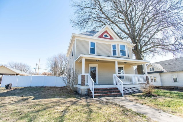 american foursquare style home with covered porch, a front lawn, and fence