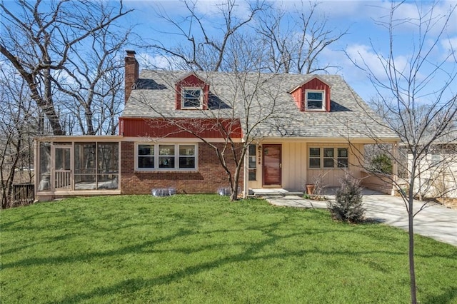 view of front of property featuring brick siding, board and batten siding, a front yard, a chimney, and a sunroom