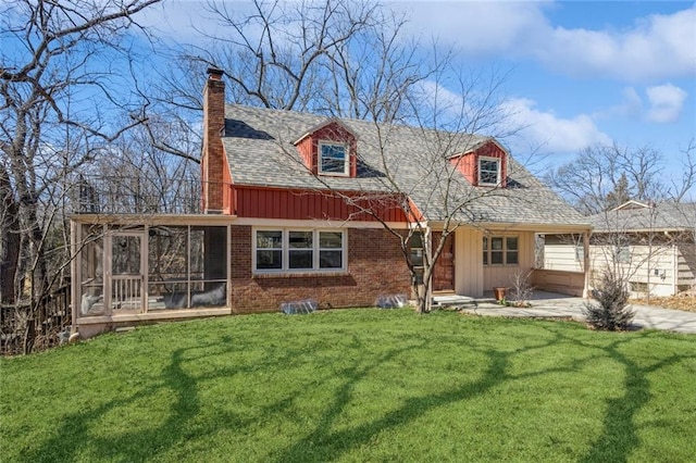 rear view of house featuring a sunroom, a chimney, a shingled roof, a lawn, and brick siding