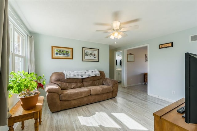 living area with visible vents, baseboards, light wood-style floors, and ceiling fan