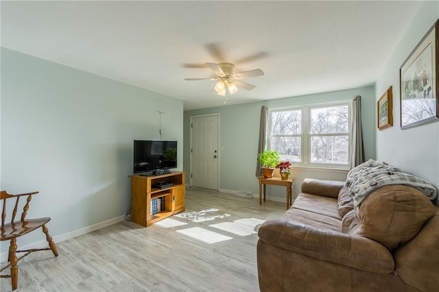 living room with baseboards, light wood-type flooring, and ceiling fan