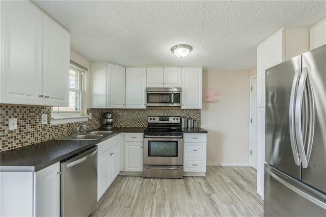 kitchen with backsplash, stainless steel appliances, dark countertops, and white cabinetry