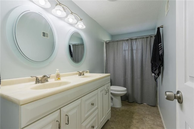 full bath featuring double vanity, visible vents, toilet, and a sink