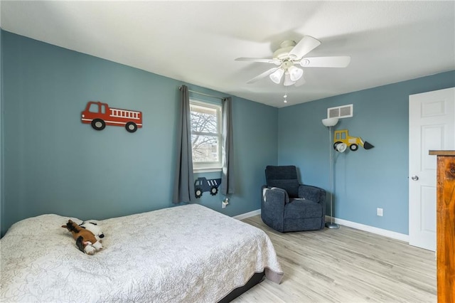 bedroom featuring visible vents, a ceiling fan, baseboards, and wood finished floors