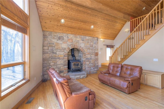 living area with stairway, a wood stove, plenty of natural light, and wood ceiling