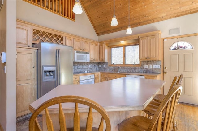 kitchen with light brown cabinets, decorative backsplash, white appliances, and decorative light fixtures