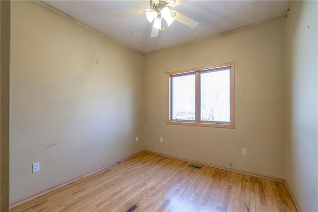 spare room with ceiling fan, baseboards, visible vents, and light wood-type flooring