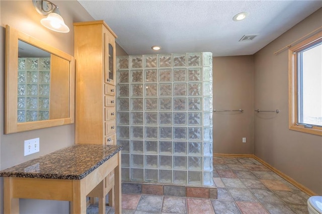 full bathroom featuring visible vents, stone finish flooring, a textured ceiling, recessed lighting, and baseboards