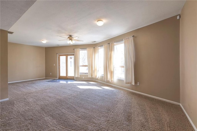 carpeted empty room with baseboards, a textured ceiling, a healthy amount of sunlight, and a ceiling fan