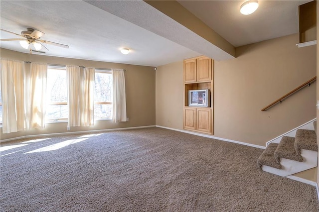 unfurnished living room featuring carpet flooring, ceiling fan, stairway, and baseboards