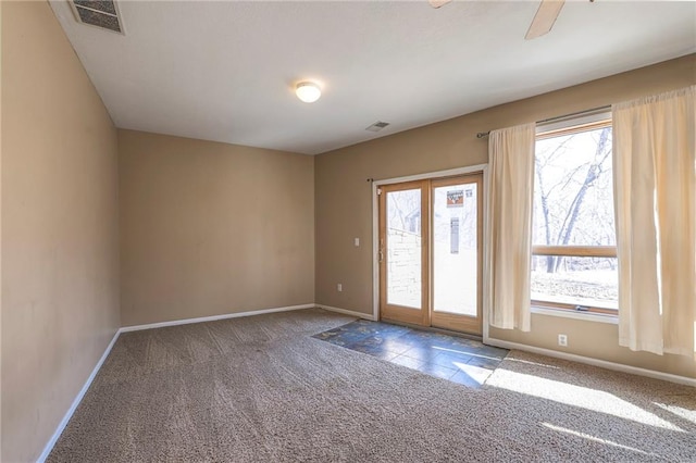 unfurnished room featuring plenty of natural light, carpet, and visible vents