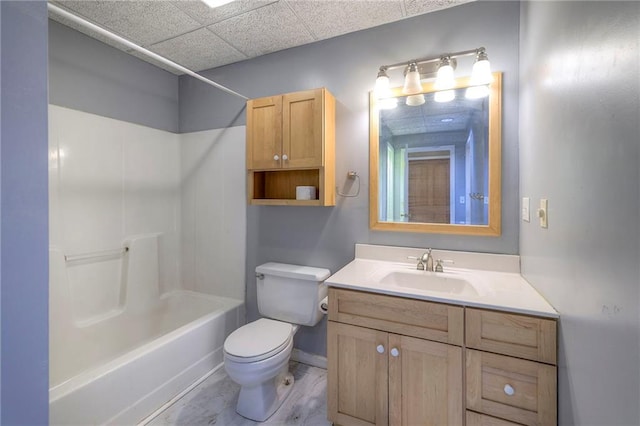 full bath with toilet, a drop ceiling, shower / tub combination, baseboards, and vanity