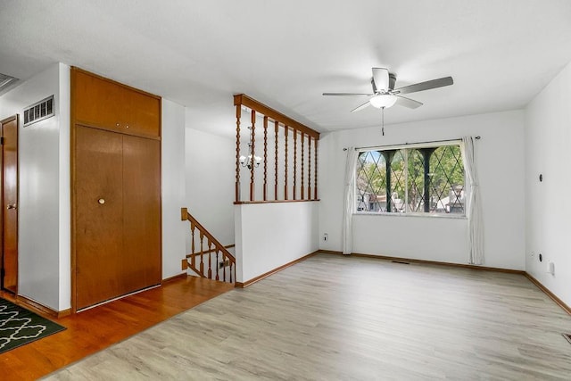 unfurnished room with ceiling fan, wood finished floors, visible vents, and baseboards