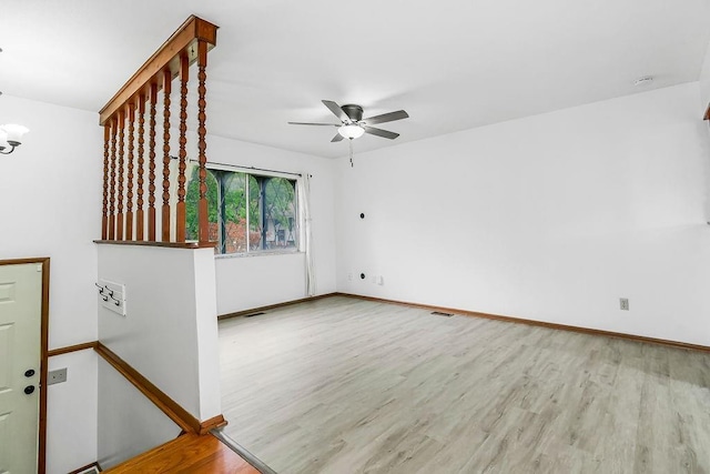 spare room with a ceiling fan, visible vents, wood finished floors, and baseboards