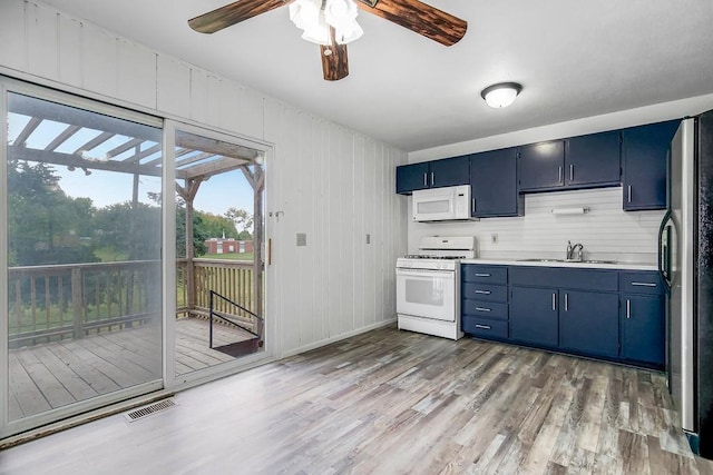 kitchen featuring white appliances, blue cabinetry, light wood-style flooring, and a sink