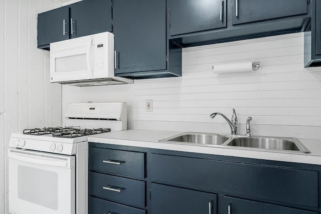 kitchen featuring white appliances, light countertops, wood walls, and a sink