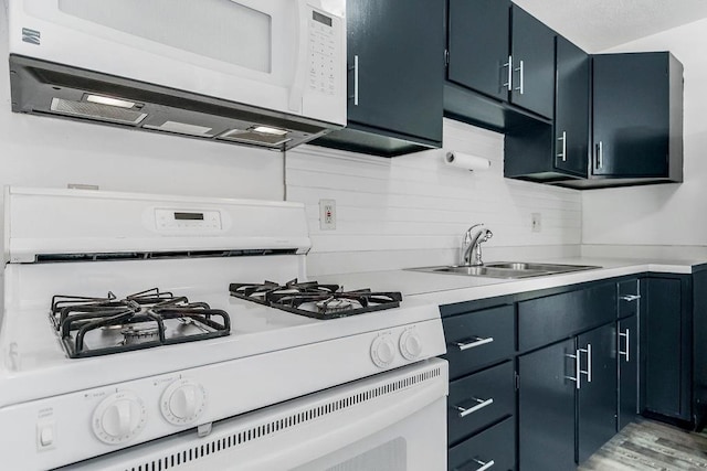 kitchen featuring tasteful backsplash, blue cabinetry, light countertops, white appliances, and a sink