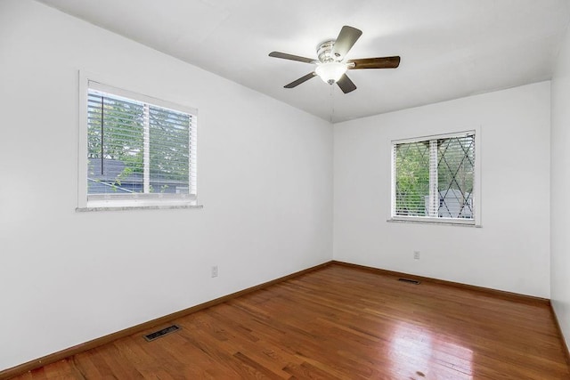 unfurnished room featuring plenty of natural light, wood finished floors, and visible vents