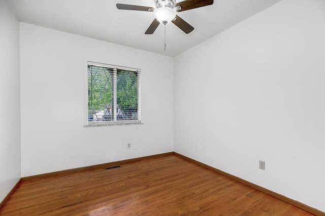 unfurnished room with a ceiling fan, wood finished floors, visible vents, and baseboards