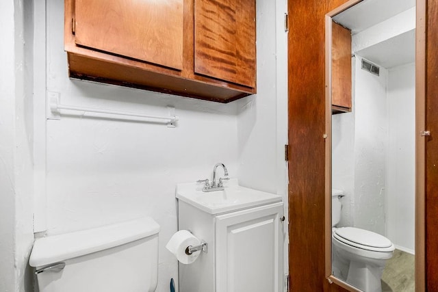 half bath with visible vents, toilet, and vanity