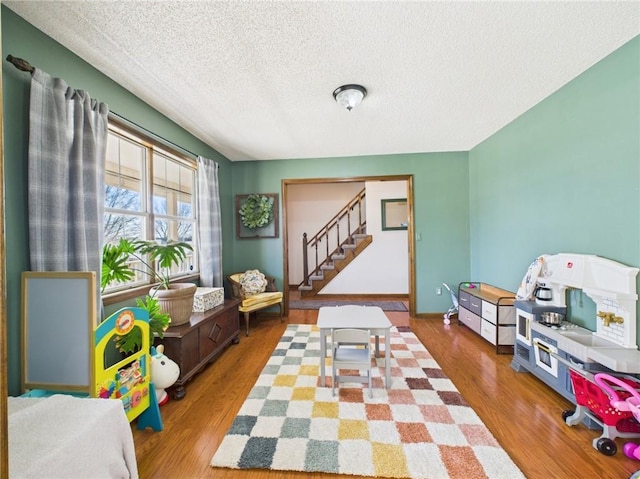 playroom featuring a textured ceiling and wood finished floors