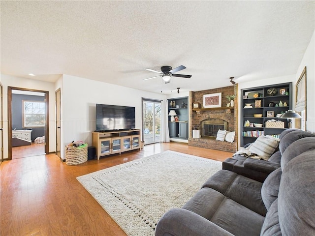 living room with a healthy amount of sunlight, a fireplace, a textured ceiling, and wood finished floors