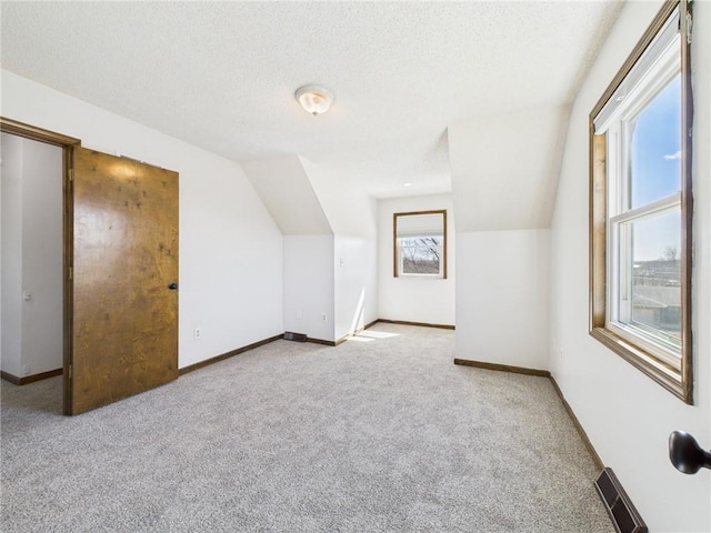 bonus room with vaulted ceiling, carpet flooring, baseboards, and a textured ceiling