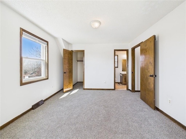 unfurnished bedroom featuring ensuite bath, baseboards, and carpet floors