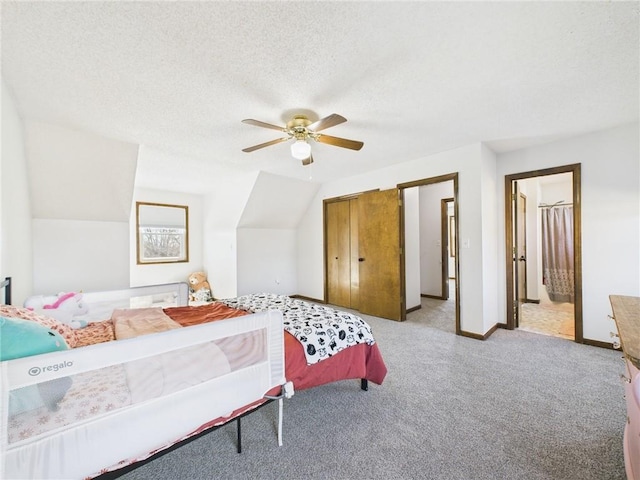 carpeted bedroom featuring baseboards, lofted ceiling, ceiling fan, a closet, and a textured ceiling