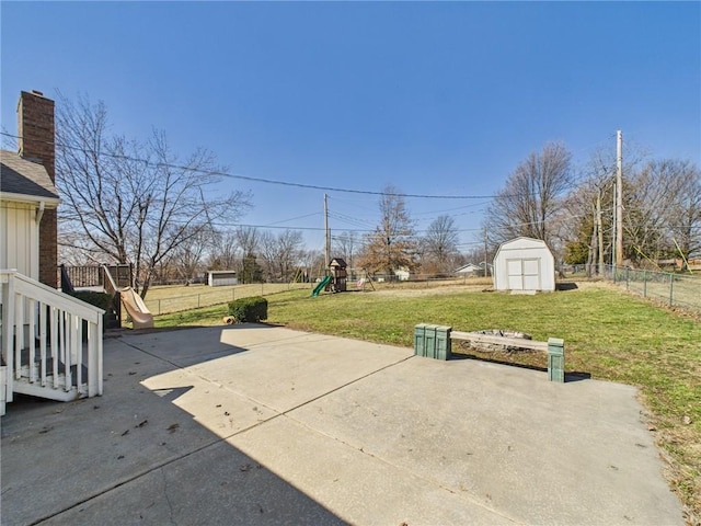 view of patio / terrace with an outbuilding, a playground, fence, and a shed