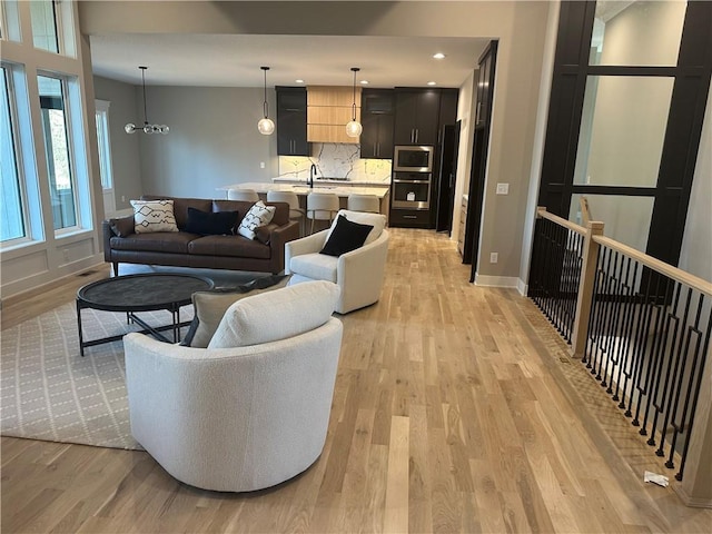 living room featuring light wood finished floors, recessed lighting, and baseboards