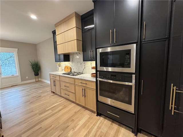 kitchen featuring oven, light wood-type flooring, backsplash, gas stovetop, and built in microwave