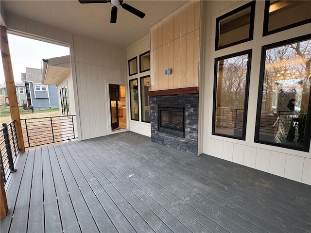 wooden deck with an outdoor stone fireplace and ceiling fan