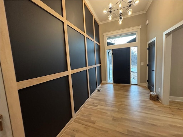 foyer featuring ornamental molding, wood finished floors, a high ceiling, an inviting chandelier, and baseboards