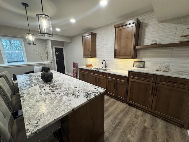 kitchen featuring a sink, open shelves, backsplash, dark wood-style floors, and light stone countertops