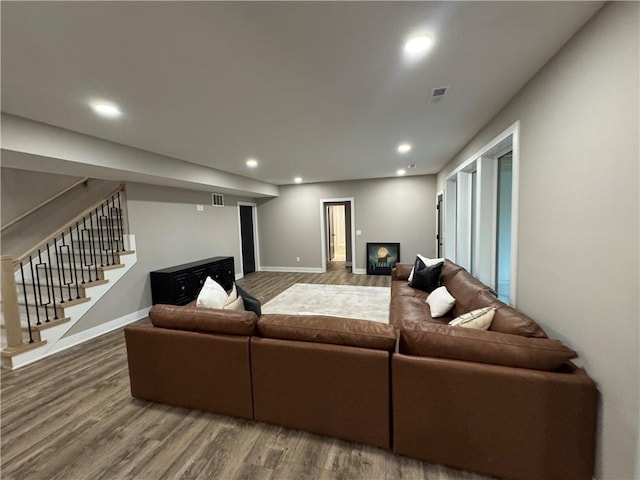 living room featuring visible vents, baseboards, stairs, recessed lighting, and wood finished floors