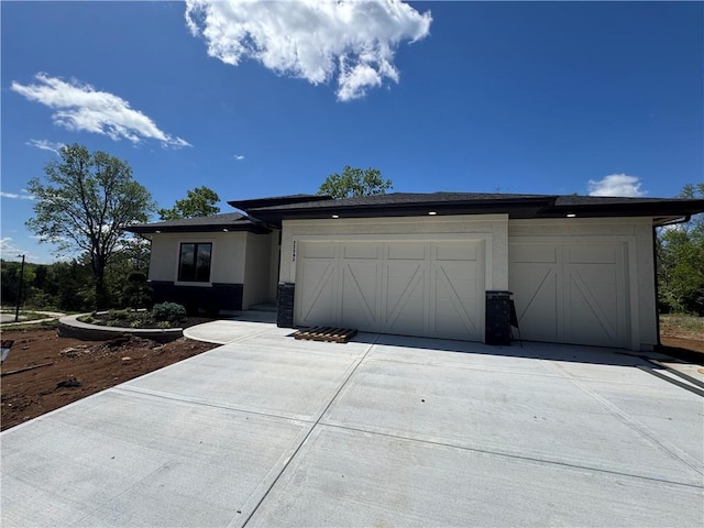 view of front of house with an attached garage, driveway, and stucco siding
