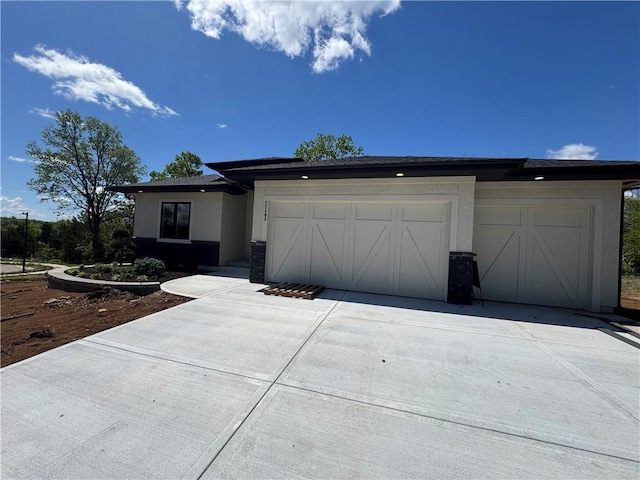 view of front of home with an attached garage, concrete driveway, and stucco siding