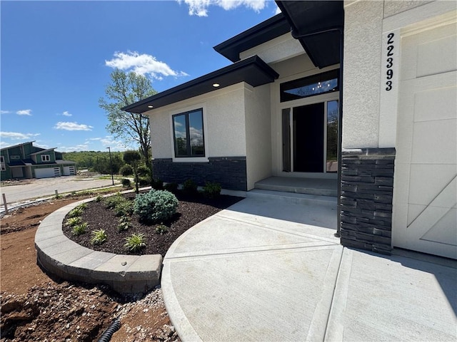 view of exterior entry featuring stucco siding and stone siding